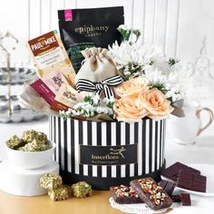 a black and white box filled with assorted candy, candies and flowers on a table