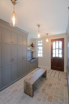 a large kitchen with gray cabinets and a wooden bench