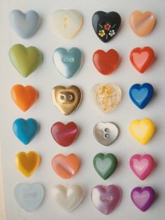 many different colored heart shaped buttons on a white surface