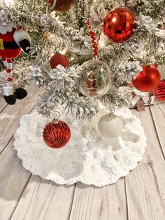 a christmas tree with ornaments on it and santa clause decorations around the base in red, white and silver