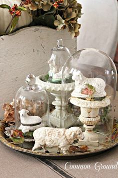 there is a glass dome with figurines in it on the tray next to a potted plant