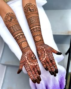 two hands with henna tattoos on them sitting next to each other in front of a white pillow