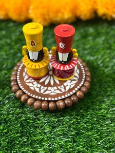 two small wooden toys sitting on top of a green field