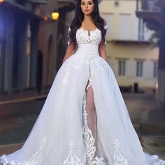 a woman in a white wedding dress standing on the street with her legs slited