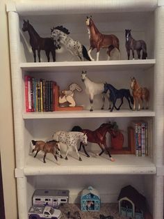 several toy horses are sitting on top of shelves