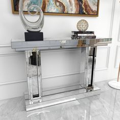 a glass and chrome console table in a living room with a painting on the wall