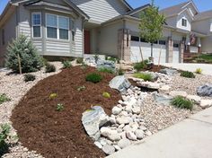 a house with landscaping in front of it and rocks on the ground next to it