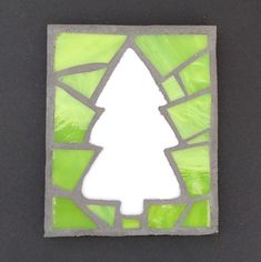 a green stained glass window with a white christmas tree on it's center piece