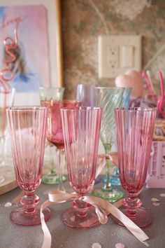 three pink wine glasses sitting on top of a table next to confetti cups