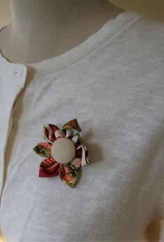 a white shirt with a flower on it and a button attached to the back of it