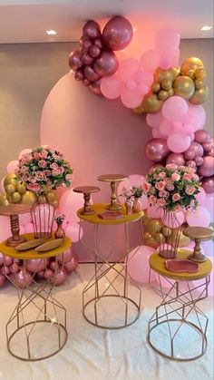 pink and gold balloons are on display in this room with chairs, tables and vases