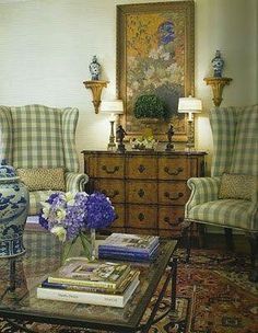 a living room filled with furniture and flowers on top of a table in front of a painting