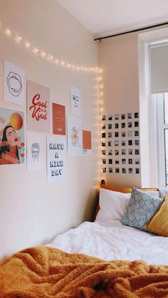 an unmade bed in a bedroom with posters on the wall and lights above it