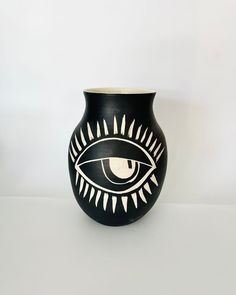 a black vase with an eye painted on it