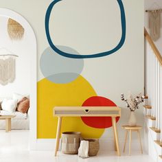 a living room with white walls and colorful artwork on the wall, along with two wooden stools