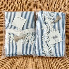 two blue and white towels wrapped in plastic on top of a wicker tablecloth