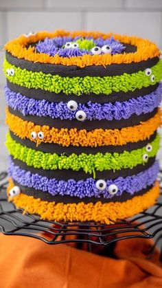 a multi - colored cake with googly eyes on it