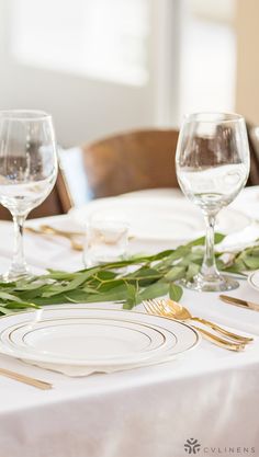 the table is set with plates, silverware and greenery for an elegant dinner