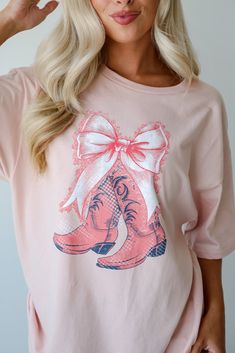 Embrace your playful side with the Boots & Bows Blush Graphic Tee! Made from a soft and breathable cotton material, this tee offers ultimate comfort and a relaxed fit, perfect for everyday wear. The blush color provides a soft, feminine touch, while the graphic design adds a hint of western flair with a whimsical twist. The short sleeves and classic crew neckline create a timeless silhouette that can be easily styled for various occasions. Ideal for casual outings, this graphic tee pairs perfect Pink Relaxed Fit T-shirt For Fall, Pink Soft-washed T-shirt For Fall, Pink T-shirt For Fall Loungewear, Cute Soft-washed Pink T-shirt, Spring Soft-washed Pink T-shirt, Bow Graphic, Graphic Tee Dress, Cute Graphic Tees, Soft Feminine