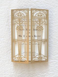 an intricate laser cut wedding card is displayed on a white background with gold trimmings