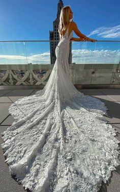 a woman in a wedding dress standing on top of a building looking at the sky