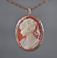 A short necklace that is based on the baroque style ... Lady Cameo adorns the design of the oval chain, which is decorated with a rose gold-plated frame. Due to the coral-colored background, Lady Cameo with her cream-colored silhouette comes out strongly. The colors create a magical interplay and make the necklace a very special and romantic piece of jewelry. Give yourself a present or make other vintage lovers happy. The matching earrings and the matching ring can be found in our shop under the following links: https://www.etsy.com/de/listing/899586984/lady-kamee-rosevergoldete-vintage?ref=shop_home_active_3&frs=1 https://www.etsy.com/de/listing/899588436/lady-cameo-rosevergoldeter-vintage-ring?ref=shop_home_active_2&frs=1 Chain length: 45 cm Beginner: approx. 2.5 cm ♥ Handmade with Love Vintage Gold Cameo Necklace, Elegant Antique Gold Cameo Necklace, Lady Cameo Necklace, Ornate Oval Cameo Necklace, Ornate Antique Gold Cameo Necklace, Matching Rings, Baroque Fashion, Vintage Lover, Short Necklace