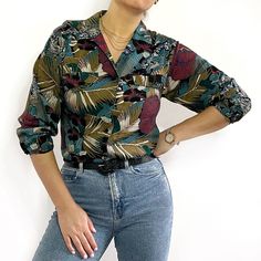 Beautiful, dark tropical print ladies shirt with long sleeves, an open v-neck collar and two chest pockets. It is made from soft, light viscose and has a straight, loose shape. Made in Romania by LNO Sportswear Associates Inc. 100% viscose. Medium size, measurements when laid flat are: Pit to pit: 49cm Waist: 46cm Hemline: 50cm Length: 58cm Sleeve length: 52cm Excellent condition. Casual Blouse With Plant Print, Casual Collared Blouse With Tropical Print, Casual Long Sleeve Tops With Plant Print, Casual Blouse With Tropical Print And Relaxed Fit, Fall Floral Print V-neck Shirt, V-neck Floral Print Fall Shirt, Trendy Tropical Print Button-up Tops, Trendy Button-up Tops With Tropical Print, Casual Floral Print V-neck Hawaiian Shirt