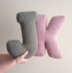 someone is holding two pillows in the shape of letters k and person's hand