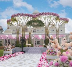 an outdoor wedding venue with pink flowers in the foreground and white columns on either side