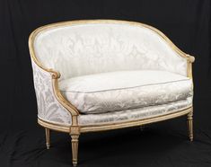 a white couch with gold trim sitting on a black background