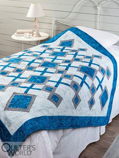 a bed with a blue and white quilt on it