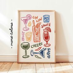 a framed art print with various drinks and cocktails on it in front of a white wall