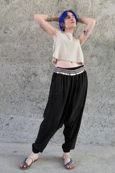 Cupro Harem Pants in black are the new member of Odana's Sustainable Outfits. Ethically handmade from Cupro fabric, these pants breathe extremely well. With silky soft feel, they are luxuriously comfortable, which makes them an impeccable choice for warm months. Cupro, also known as Vegan Silk fabric is made from cotton linters. We use Oeko-Tex-certified, bio-degradable Cupro produced with a zero-waste policy. Breath Harem Pants are available in a variety of size choices from XS to big and tall. Indulge yourself with these drop crotch pants, enjoy the soft silky touch, the gentle flowy fit, and all the compliments you'll get! These pants would make a great couple with sandals, sneakers, our crop tops, and Shaman top. This one would be a luxurious addition to your sustainable wardrobe. This Sustainable Outfits, Baggy Pants Women, Cupro Fabric, Cotton Harem Pants, Black Harem Pants, Drop Crotch Pants, Harem Pants Women, Womens Trousers, Pants Plus Size