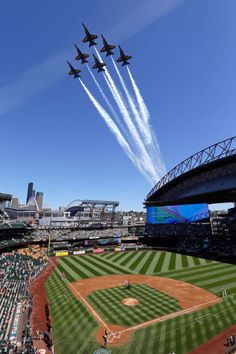 four jets flying in formation over a baseball field