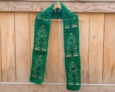 a green crocheted scarf hanging on a wooden wall