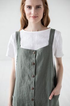 a woman wearing a green and white dress with buttons on the front, standing in front of