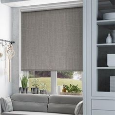 a living room filled with furniture and a window covered in grey roller shade coverings