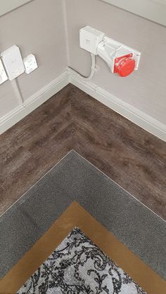 an electrical outlet in the corner of a room with wood flooring and white walls