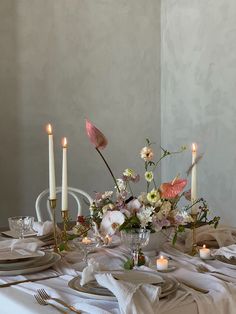 a table set with flowers, candles and plates