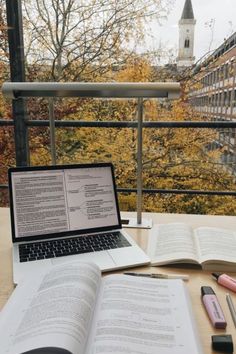 an open book sitting on top of a table next to a laptop computer and pen