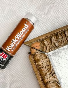 a bottle of paint sitting on top of a white surface next to a mirror frame