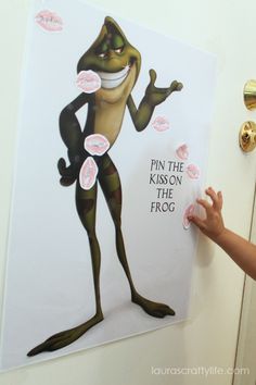 a young child holding up a paper cut out of a cartoon character that says pin the krapson on the frog