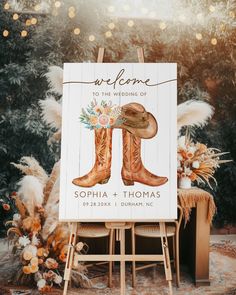 a welcome sign with boots and flowers on it for a western themed wedding in the woods