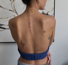 a woman with tattoos on her back standing in front of a painting