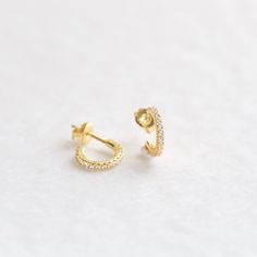 "These tiny open-hoop stud earrings are adorned with brilliant cubic zirconia gemstones. They're the perfect huggie hoop size for layering with other dainty hoops and studs. A dainty, elegant and versatile addition to your everyday lineup. ∙ Sold as a PAIR * D E T A I L S * ∙ Material: .925 Sterling Silver or 18K Gold Plated over .925 Sterling Silver ∙ Stone: White Cubic Zirconia ∙ Dimensions: Outer diameter: 11mm // Inner diameter: 7mm ∙ Hypoallergenic & nickel-free * P A C K A G I N G * ∙ Tiny Hoop Huggie Earrings For Anniversary, Pierced Cubic Zirconia Huggie Diamond Earrings, Minimalist Cubic Zirconia Hoop Diamond Earrings, Cubic Zirconia Huggie Jewelry, Small Hoop Cubic Zirconia Huggie Earrings, Cubic Zirconia Small Hoop Earrings, Cubic Zirconia Huggie Earrings With Ear Wire As Gift, Small Hoop Cubic Zirconia Earrings With Ear Wire, Dainty Cubic Zirconia Small Hoop Huggie Earrings