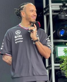 a man with dreadlocks standing in front of a microphone and wearing a black shirt