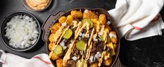 a tray filled with tacos, onions and other food on top of a table