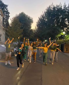 a group of people walking down a street with their arms in the air and one person holding up her hand