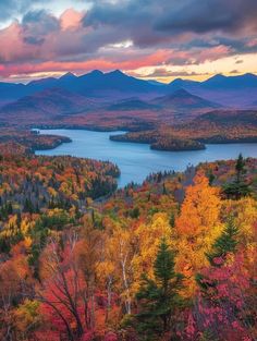 the mountains are covered in autumn foliage and trees with colorful leaves on them as the sun sets