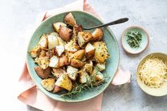 a blue bowl filled with potatoes and parmesan cheese on top of a pink napkin